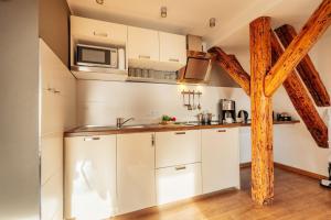 a kitchen with white cabinets and a wooden beam at Bergpanorama in Sankt Andreasberg