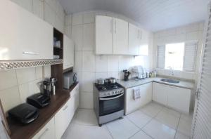 a white kitchen with a stove and a sink at Pousada da Juh in Campo Grande