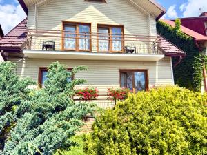 a white house with a balcony and trees at Willa Świerk in Susiec