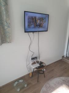 a flat screen tv hanging on a wall with a chair at Apartmani Zoka in Niš