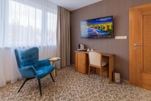 a hotel room with a blue chair and a desk at Kontakt Wellness Hotel in Tatranská Lomnica