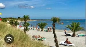 people on a beach with palm trees and the ocean at Damm Hotell in Frederikshavn