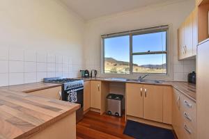 a kitchen with a stove and a sink and a window at Somerville Wine Cottage Hideaway 3-Bedroom Cottage Near Broke Wineries in Broke