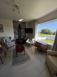 a living room with a large window and a couch at Meadow View Cottage in Clooncullin Bridge