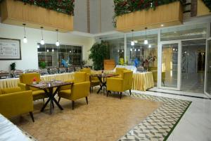 a dining room with tables and yellow chairs and a restaurant at Dubai Palace Hotel in Sambriāl