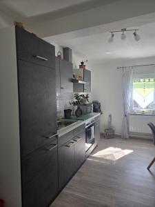 a kitchen with gray cabinets and a sink and a window at Buchenau an der Lahn 