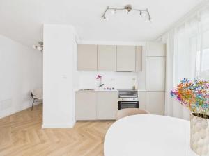 a white kitchen with white cabinets and a table at Apartament HUZAR 2 in Białystok