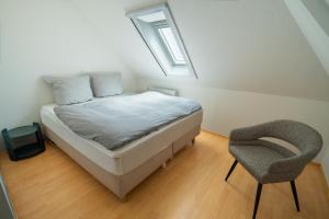 a bedroom with a bed with a chair and a window at Erasmus WaldBlick Ferienhaus mit Ausblick in Saarburg