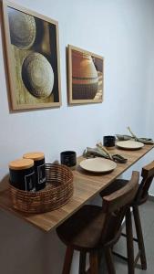 a table with chairs and plates and pictures on the wall at Villa Bela - Lofts - cama queen e ar-condicionado in Iguaba Grande
