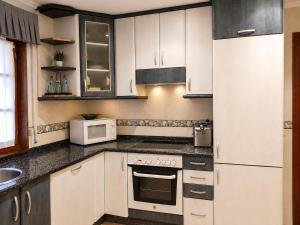 a kitchen with white cabinets and white appliances at El Rincón de Luarca in Luarca