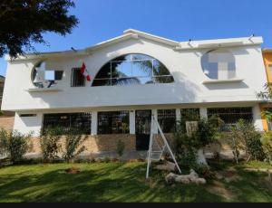 a white house with an arched window at Hospedaje Cocos House Talara - amplias habitaciones, Buena Ubicacion in Talara +4 photos