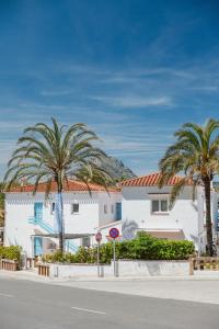 a street with two palm trees in front of a building at Los Bungalows Del Arenal in Jávea