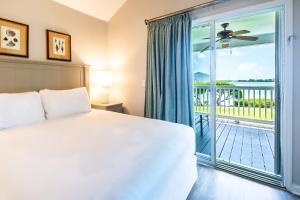 a bedroom with a bed and a large window with a balcony at Blue House Getaway - 2BR 3BA Coastal Villa in Duck Key