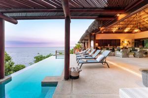 an outdoor pool with lounge chairs and the ocean at 2024 - Villa Serena in Santa Cruz Huatulco