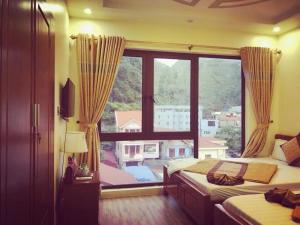 a bedroom with two beds and a large window at Hoàng Phúc home - restaurant in Cat Ba +1 photo