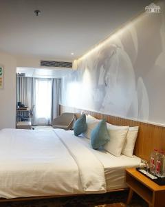 a bedroom with a large white bed with blue pillows at The Atlantiis Suites Nr Vishwanath Temple in Varanasi