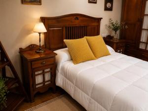 a bedroom with a white bed with yellow pillows at El Rincón de Luarca in Luarca