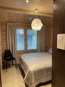 a bedroom with a bed and a chair and a chandelier at Villa Loiste Himos Chalet with Hot Tub in Jämsä +22 photos