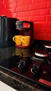 a kitchen counter with a stove top with two yellow mugs at Loft Moderno 3 in Volta Redonda
