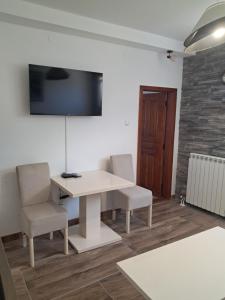 a room with a white table and chairs and a tv at Apartment Nikola R in Žabljak