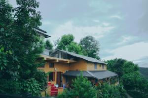 a yellow house with a balcony on a hill at Mellowmine Premier in Kokliyal Gaon