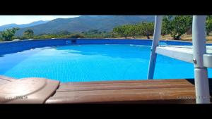 a large blue swimming pool with a wooden bench at FINCA El LABRAO DE ALARDOS in Candeleda