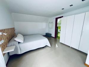a bedroom with a white bed and white cabinets at Casa do Prado in Pontevedra