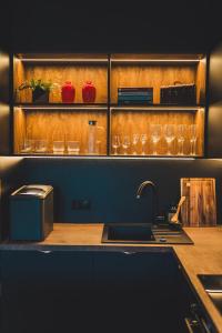 a kitchen with a sink and glasses on a shelf at Jacuzzi Siesławska Top Apartment in Busko-Zdrój