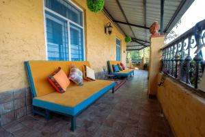 a porch with a bench with pillows on it at Mellowmine Premier in Kokliyal Gaon +15 photos