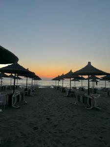 a group of chairs and umbrellas on a beach at David’s apartments in Hamallë