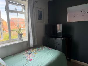 a bedroom with a bed with a television and a window at Eastbourne in Pevensey
