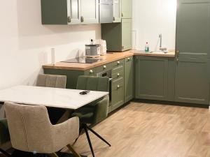 a kitchen with green cabinets and a table and chairs at Edna House in Montigny-lès-Cormeilles