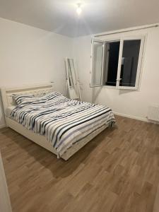 a white bedroom with a bed and a window at Edna House in Montigny-lès-Cormeilles