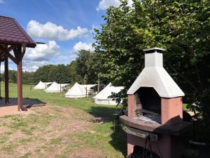 a brick oven in a field with tents in the background at Mazury Glamping Kruklanki Polana Życzeń in Kruklanki