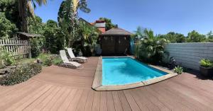 a swimming pool on a wooden deck with two lounge chairs at studio P ti koin trankil in La Possession