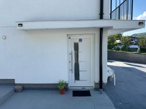 a white door on a white building with a chair at Sarajevo Days in Binježevo