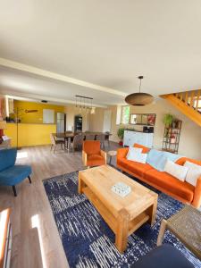 a living room with an orange couch and a table at Mon Pré Vert in Saint-Ellier-du-Maine