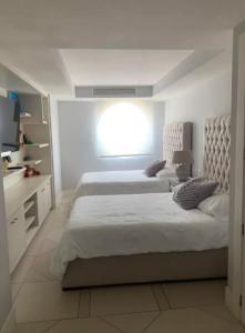 a white bedroom with two beds and a window at Bay View Grand Marina with jacuzzi- North Tower in Ixtapa +13 photos