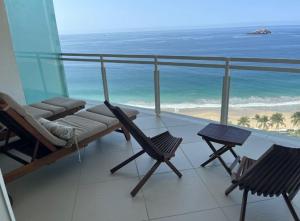 a balcony with a hammock and chairs and the beach at Bay View Grand Marina with jacuzzi- North Tower in Ixtapa
