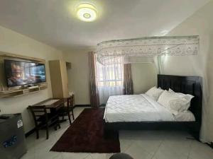 a bedroom with a bed and a desk and a television at Qwema Guest House in Nairobi +1 photo
