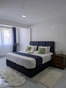a bedroom with a large bed with a blue headboard at Qwema Guest House in Nairobi