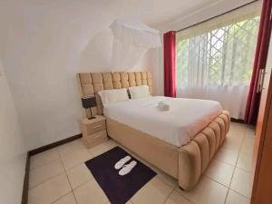 a bedroom with a large bed with white shoes on the floor at Qwema Guest House in Nairobi