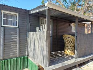 a cabin with a fence and a chair on a deck at Neat Haven Self Catering in Grahamstown