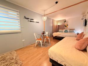 a bedroom with two beds and a table and a window at Estadía con opción jacuzzi Villa Alemana in Villa Alemana +16 photos