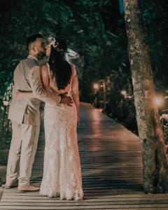 a bride and groom kissing on a boardwalk at night at Almonds & Corals Boutique Hotel in Puerto Viejo