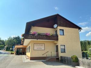 a building with a balcony with flowers on it at Gasthaus Mossauer in Feistritz bei Knittelfeld