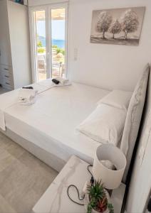 a large white bed in a room with a window at Sadova Messinia Pearl Cozy Seafront House in Avía