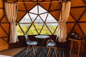a room with a large window with chairs and a table at Gaiatri Holistic Glamping in Tepoztlán