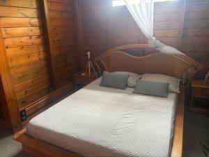 a bedroom with a wooden bed with two pillows at Le Bananawi in Pointe-Noire