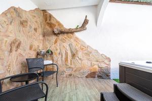 a room with a rock wall with chairs and a table at Casa Huertas del Palmar in Teror